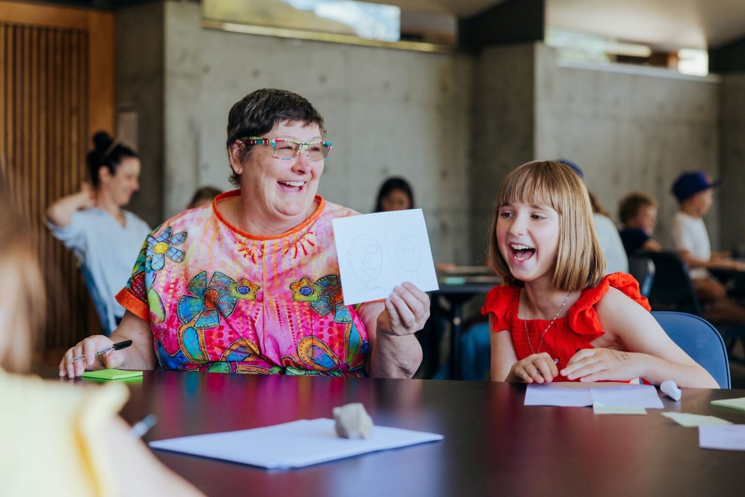 Two participants laughing together at a table during the Wild, Everyday Adventures comic workshop